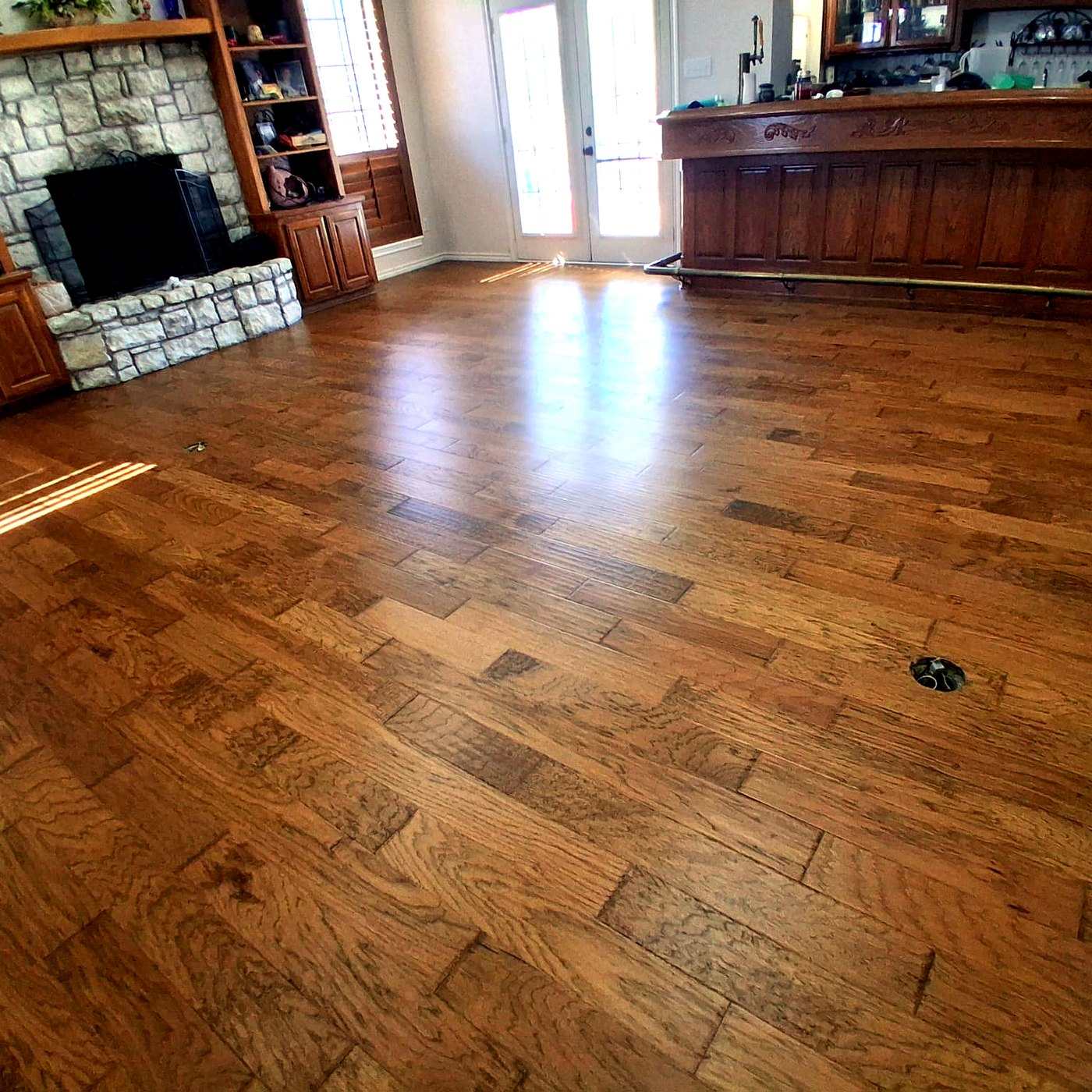 FloorFlash hand-scraped hardwood installation in a DFW open-concept living and dining room with stone fireplace and bar seating