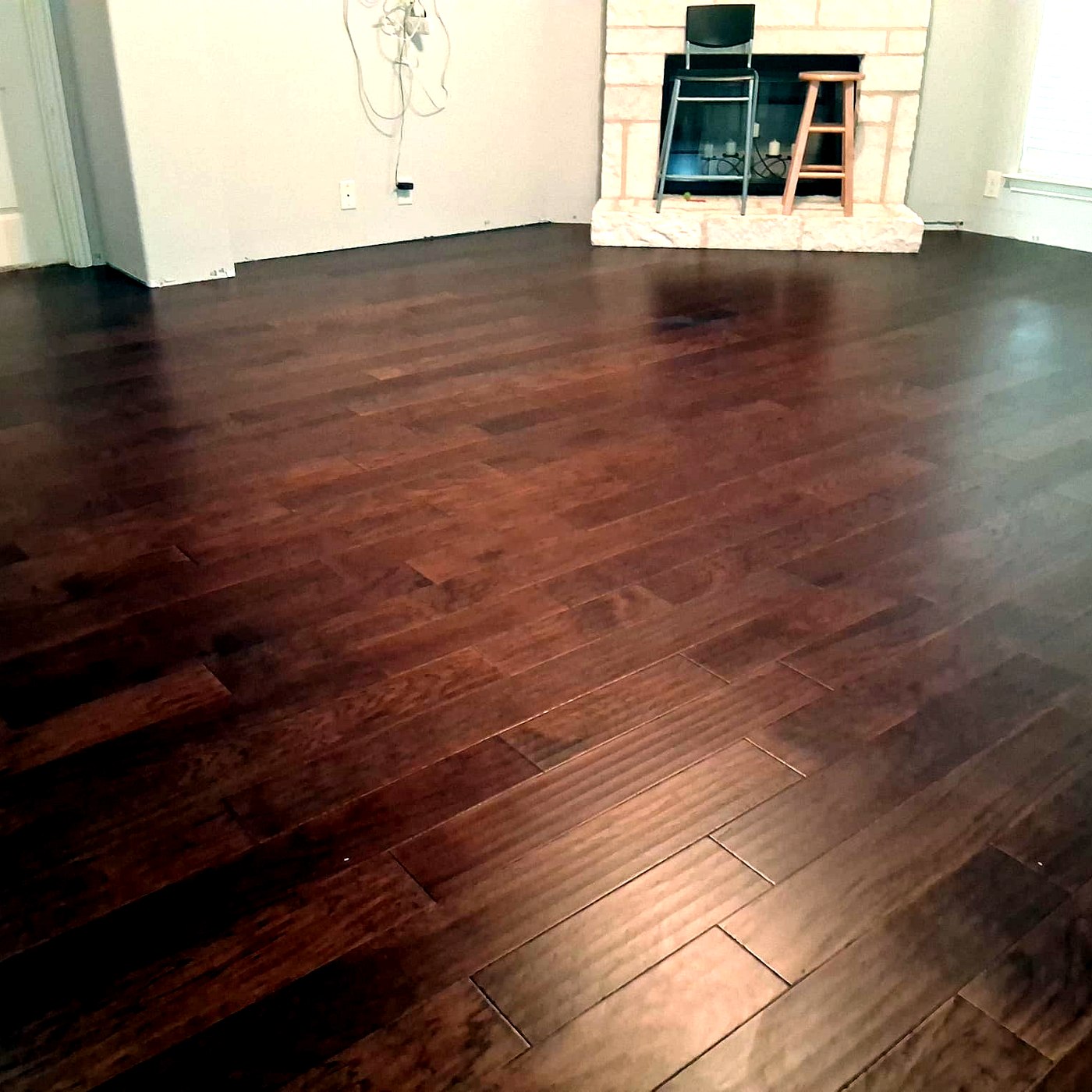 FloorFlash glossy cherry-walnut hardwood floor installed in a Dallas living room with stone fireplace