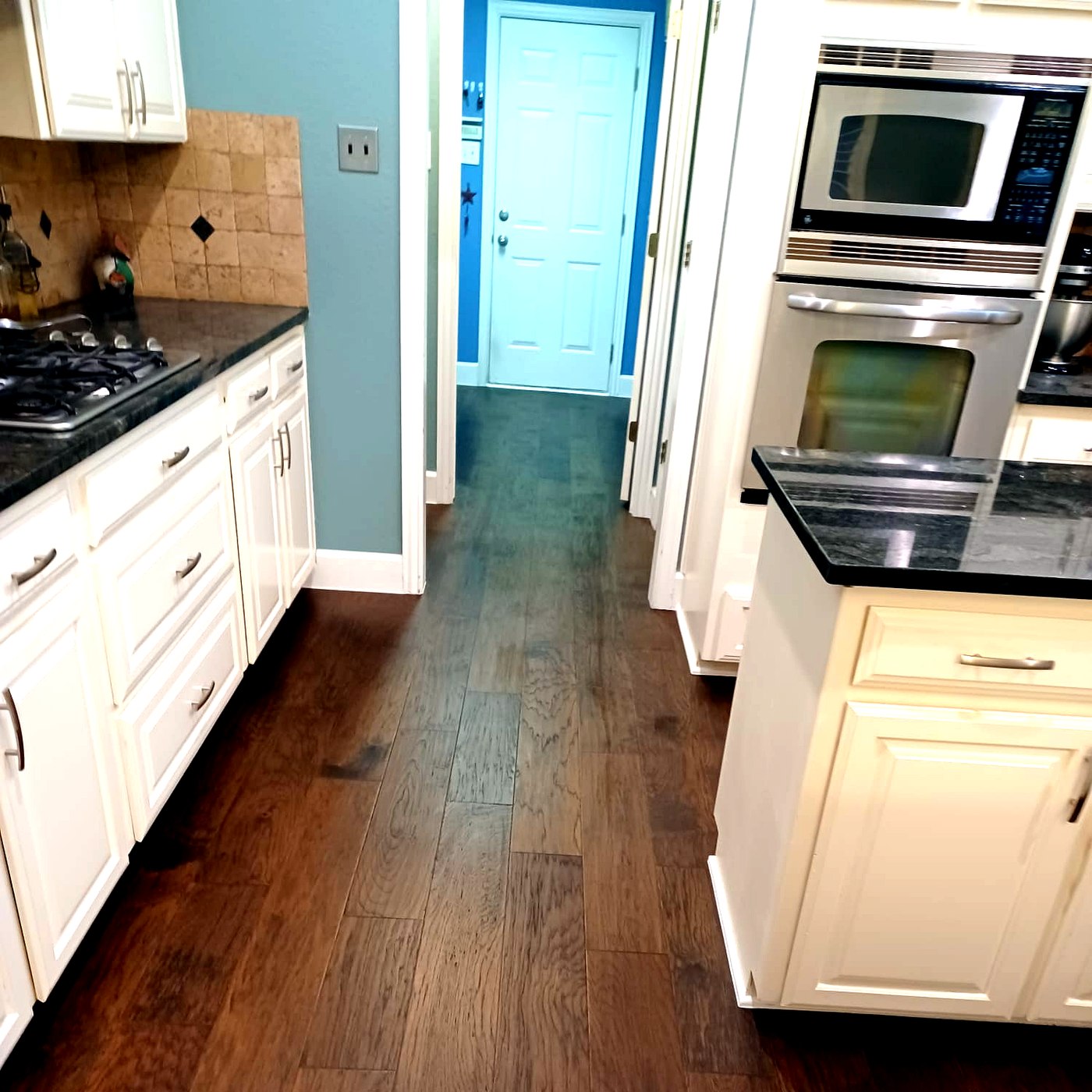 FloorFlash hand-scraped hardwood install in a DFW kitchen with white cabinetry and bright blue accent door