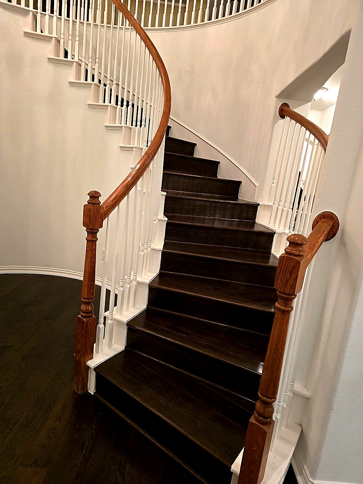 FloorFlash curved staircase install in DFW with dark stained treads, white spindles, cherry-stained handrail