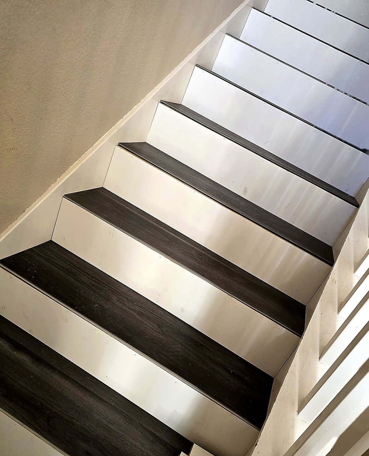 FloorFlash signature two-tone staircase install overhead view: charcoal treads, crisp white risers, DFW custom finish