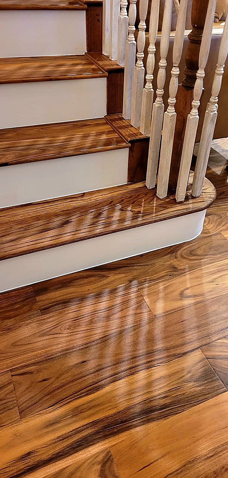 FloorFlash tigerwood staircase landing install in DFW with rounded bullnose, white spindles, cherry-stained turned post
